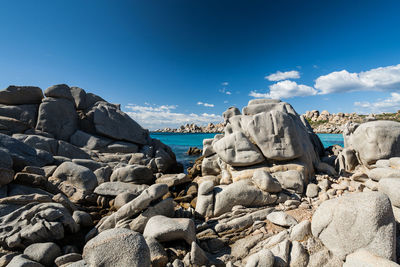 Panoramic shot of rocks on beach against blue sky