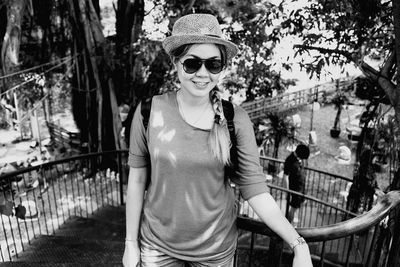 Portrait of smiling woman wearing sunglasses standing on staircase