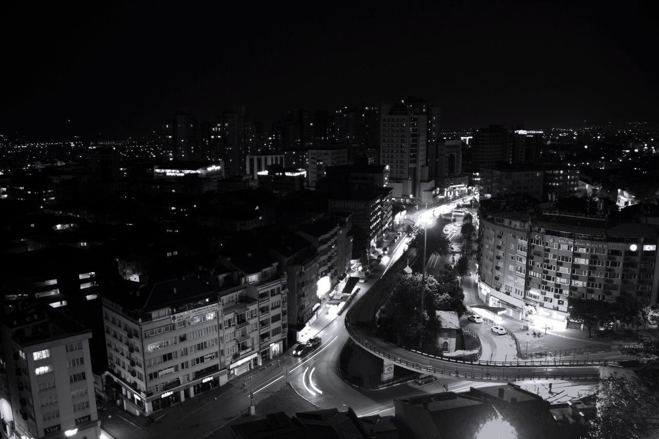 HIGH ANGLE VIEW OF ILLUMINATED STREET AMIDST BUILDINGS AT NIGHT