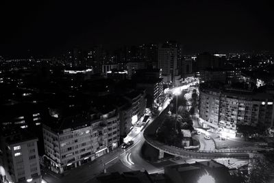 High angle view of illuminated street amidst buildings in city at night