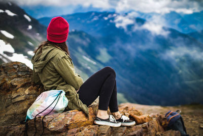 Rear view of woman sitting on rock