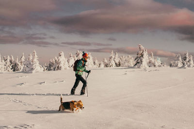 Woman with pet dog walking on snow