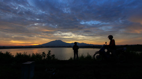 Silhouette people on mountain against sky during sunset