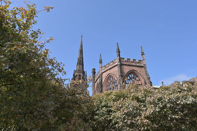 Low angle view of trees and building against sky