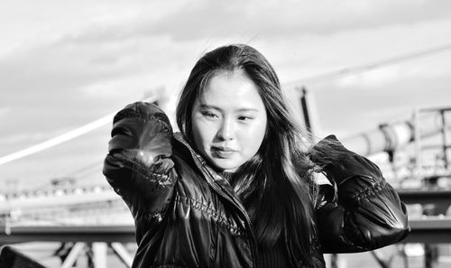 Portrait of young woman looking at camera against sky