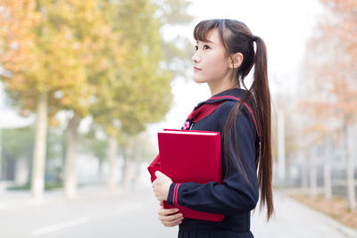 Side view of beautiful young woman standing on road