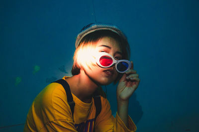 Portrait of woman wearing sunglasses against wall