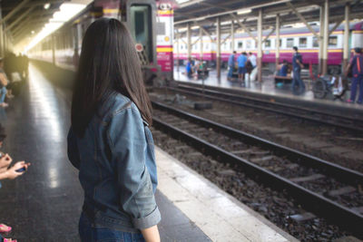 Rear view of woman standing at railroad station