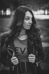 Thoughtful beautiful young woman standing in park