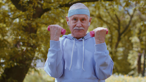 Portrait of senior man exercising with dumbbells in park