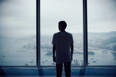 Rear view of man looking through window