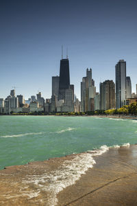 Sea by buildings against clear sky