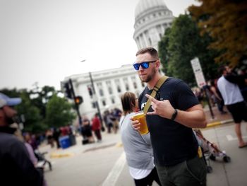 Man wearing sunglasses and holding beer standing outdoors