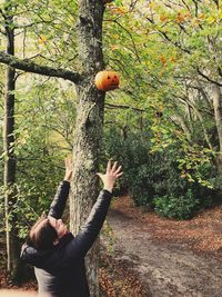 Rear view of woman standing by tree trunk