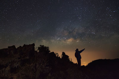 Silhouette man standing on field against sky at night