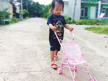 Full length of cute girl holding pink while standing outdoors