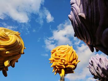 Low angle view of yellow statue against sky