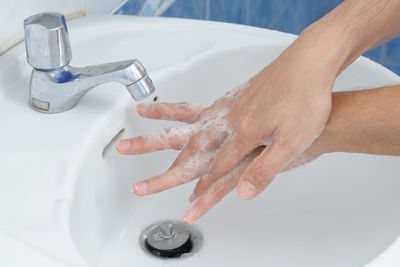 Cropped image of man washing hands in sink