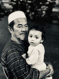 Portrait of cute granddaughter carried by grandfather outdoors