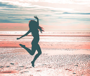 Full length of woman on beach against sky during sunset