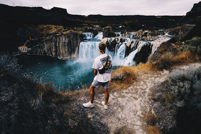 Rear view of man standing by waterfall