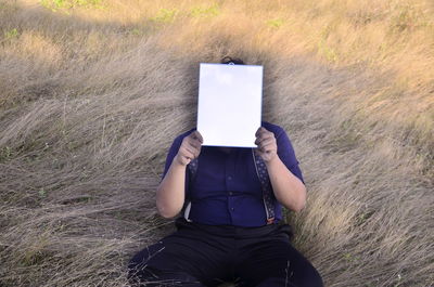 Midsection of person holding mobile phone in field