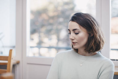 Woman sitting against window at college dorm