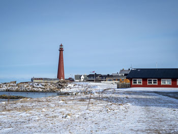 Lighthouse and buildings at andenes in vesteralen, norway, in winter with snow