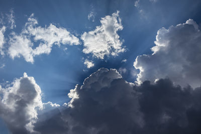 Low angle view of sunlight streaming through clouds