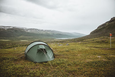 Tent on field by mountain against sky