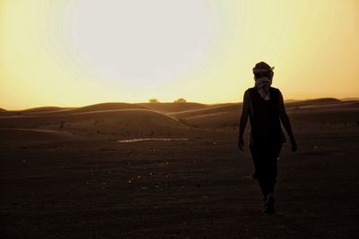 Silhouette of man walking in desert during sunset