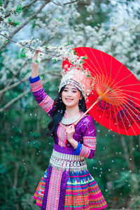 Low angle view of smiling girl standing against tree