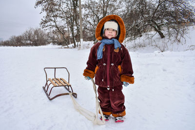 Little child pulling a sled in the snow. the kid is riding on a sleigh. 