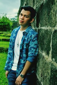 Portrait of young man standing by wall