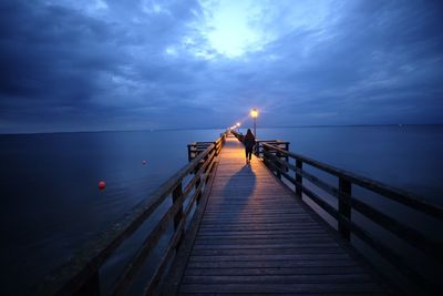 Man on pier over sea against sky