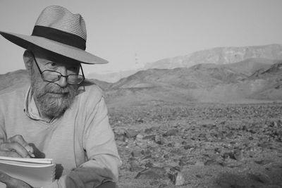 Portrait of man wearing hat while sitting on mountain