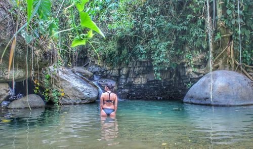 Full length of shirtless man in water at forest