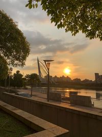 Swimming pool by lake against sky during sunset