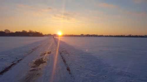 Scenic view of frozen lake against sky during sunset