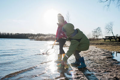 Brother and sister playing with nets and toys at a sunny beach