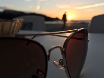 Close-up of sunglasses on car against sky during sunset