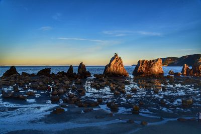 Rocks at beach against sky