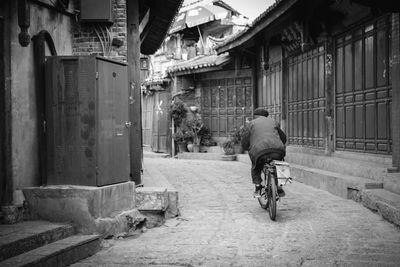 Rear view of man cycling on bicycle in city