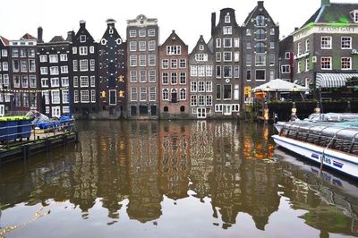 Reflection of houses in canal against sky