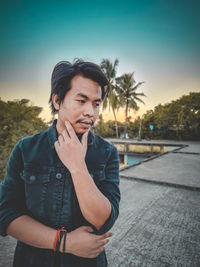 Portrait of young man looking away against sky