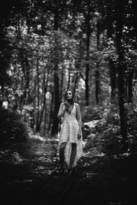 Portrait of young woman standing on footpath in forest