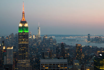 Illuminated cityscape against sky during sunset