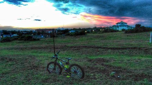 Bicycle on field against sky during sunset