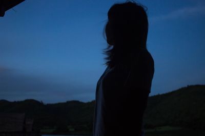 Silhouette of woman against clear sky at night