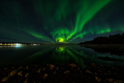 Aurora borealis over river against sky at night